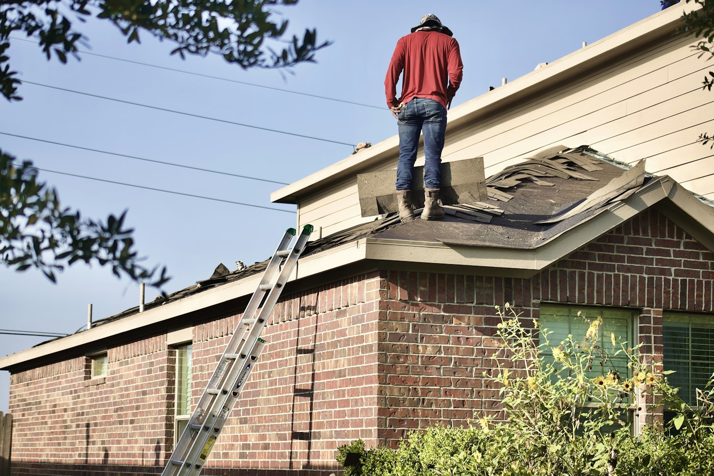 Roofer standing on a roof inspecting a brick house